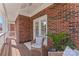 Inviting covered brick porch features a cozy chair, striped pillows, and a view of the surrounding neighborhood at 108 Forrester Ave, Belmont, NC 28012