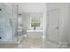 Bright bathroom featuring a glass-enclosed shower, freestanding tub, sleek fixtures, and marble tile at 1522 Napa Nw St, Concord, NC 28027