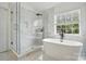 Bright bathroom featuring a glass-enclosed shower, freestanding tub, sleek fixtures, and marble tile at 1522 Napa Nw St, Concord, NC 28027