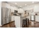 Bright kitchen with stainless steel appliances, granite counters, white cabinets, an island with seating, and wood floors at 2066 Vermount Way, Indian Land, SC 29707