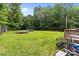 Large backyard with lush greenery, wooden deck, trampoline, and hot tub nestled among the trees at 2146 Marwood Ln, Albemarle, NC 28001