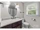Bright bathroom with a dark wood vanity, granite countertop, oval mirror, and natural light from the window at 2146 Marwood Ln, Albemarle, NC 28001
