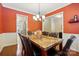 Warm dining room with dark wood floors, orange walls, and a stylish chandelier over the marble table at 3106 Crosswind Dr, Fort Mill, SC 29707