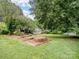 Lush backyard view featuring raised garden beds and a sunroom, framed by mature trees and verdant lawn at 3327 Archdale Dr, Charlotte, NC 28210