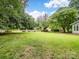 Spacious backyard with a wooden fence, mature trees, fire pit, and a storage shed at 3327 Archdale Dr, Charlotte, NC 28210