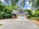 Charming home with a two-car garage and dormer, set amidst lush greenery, features a gray facade and brick accents at 3327 Archdale Dr, Charlotte, NC 28210