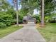 Nestled between mature trees, this home features a long driveway leading to a facade with brick accents at 3327 Archdale Dr, Charlotte, NC 28210