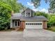 Charming home with a two-car garage and dormer, set amidst lush greenery, features a gray facade and brick accents at 3327 Archdale Dr, Charlotte, NC 28210