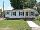 Charming single-story home with white siding, black shutters and well-maintained lawn and a walkway at 6225 Macon St, Charlotte, NC 28208