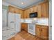 Kitchen featuring wooden cabinetry, white appliances, and tile backsplash at 6533 Derby Nw Ln, Concord, NC 28027