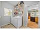 Bright laundry room featuring a washer, dryer and ample storage shelving beside a window letting in natural light at 6533 Derby Nw Ln, Concord, NC 28027