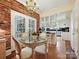Bright breakfast nook with a glass table, brick accent wall, and open access to the kitchen at 828 Colville Rd, Charlotte, NC 28207