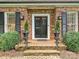 Close up of the front door, featuring brick steps, black shutters, and decorative landscaping at 828 Colville Rd, Charlotte, NC 28207