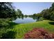 Scenic backyard view overlooking a serene lake, lush green lawn, and surrounding mature trees at 8356 Meadow Lakes Dr, Charlotte, NC 28210