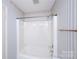 Clean bathroom with a combination shower-bathtub, featuring striped wallpaper and a bright white interior at 8356 Meadow Lakes Dr, Charlotte, NC 28210