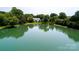 Aerial view showcases a multi-story home nestled by a tranquil pond and surrounded by lush trees at 8356 Meadow Lakes Dr, Charlotte, NC 28210