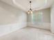 Empty dining room boasts carpet flooring, a decorative lighting fixture, and wainscoting at 8603 Robinson Meadow Ct, Charlotte, NC 28277