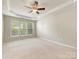 Spacious main bedroom featuring a ceiling fan, tray ceiling, and large windows at 8603 Robinson Meadow Ct, Charlotte, NC 28277