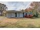 Rear view of the house featuring a stained wooden deck, light-green brick, and backyard at 8607 Larchmont Cir, Charlotte, NC 28214