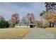 Long angle shot of a home with an ample front yard, light-green brick, and connected carport at 8607 Larchmont Cir, Charlotte, NC 28214