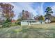 Exterior shot of the home with sprawling lawn, light green brick, and mature trees at 8607 Larchmont Cir, Charlotte, NC 28214