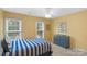 Cheerful bedroom featuring a blue and white bedspread, blue dresser, and bright yellow walls at 9423 Wood Ridge Dr, Charlotte, NC 28277