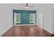 Cozy bedroom with hardwood floors, large windows, a ceiling fan, and a decorative teal accent wall at 16909 Red Cow Rd, Charlotte, NC 28277