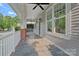 A covered porch featuring gray slate flooring, white railings, brick column bases, and outdoor ceiling fans at 16909 Red Cow Rd, Charlotte, NC 28277