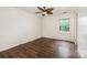 Bedroom with dark hardwood floors, a window, white walls, and a ceiling fan at 1802 Deer St, Charlotte, NC 28214