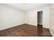 An empty bedroom featuring dark hardwood floors, white walls, and a door to a closet at 1802 Deer St, Charlotte, NC 28214