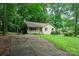 A rustic one-story home with a brick exterior, accessed by a driveway, nestled among trees and green landscape at 1802 Deer St, Charlotte, NC 28214