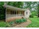 A charming brick home features a cozy front porch, complemented by green landscaping and mature shade trees at 1802 Deer St, Charlotte, NC 28214