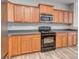 Kitchen featuring wood cabinets, stainless steel microwave, black range, and grey countertops at 2169 Belle Vernon Ave, Charlotte, NC 28210