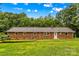 This is a beautiful single story brick house with a grassy yard and surrounded by mature trees in the background at 44092 Woodhurst Rd, New London, NC 28127