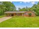 Charming brick home featuring a well-manicured lawn, mature trees, and a convenient covered carport at 44092 Woodhurst Rd, New London, NC 28127