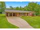 Inviting brick home with a long driveway, a carport, and a well-kept lawn with mature landscaping at 44092 Woodhurst Rd, New London, NC 28127