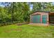 Outbuilding with garage and attached carport with a beautiful lush green lawn and mature trees at 44092 Woodhurst Rd, New London, NC 28127