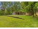 View of outbuilding with garage, attached carport and storage shed with a lush green lawn in a country setting at 44092 Woodhurst Rd, New London, NC 28127