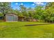 View of outbuilding with garage, attached carport and storage shed with a lush green lawn in a country setting at 44092 Woodhurst Rd, New London, NC 28127