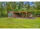 Outbuilding with garage, attached carport and storage shed with a lush green lawn and mature trees at 44092 Woodhurst Rd, New London, NC 28127