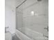 Bright bathroom featuring a shower-over-tub combination with white tiles and a sleek glass door at 515 N Church St # 305, Charlotte, NC 28202