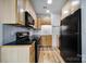 Galley kitchen featuring light wood cabinets, black appliances, and a sleek countertop at 515 N Church St # 305, Charlotte, NC 28202