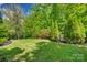 Serene backyard featuring a lush lawn, mature trees, and a charming playhouse, creating a peaceful outdoor oasis at 5518 Morris Hunt Dr, Fort Mill, SC 29708