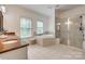 Bright bathroom with dual windows, standalone tub, and glass shower enclosure at 5518 Morris Hunt Dr, Fort Mill, SC 29708