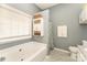 Bathroom with jacuzzi tub and white cabinets for storage with a herringbone tile floor at 5829 Andrew Ward Ave, Charlotte, NC 28216