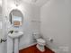Powder room with pedestal sink, oval mirror, and neutral finishes at 6532 Prosperity Commons Dr, Charlotte, NC 28269
