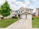 Inviting two-story home featuring a stone facade, spacious driveway, and lush green lawn at 6532 Prosperity Commons Dr, Charlotte, NC 28269