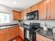 Galley kitchen features wood cabinets and modern black appliances at 6532 Prosperity Commons Dr, Charlotte, NC 28269