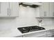 Close up of kitchen gas range and white marble backsplash in updated kitchen at 9930 Cask Way, Huntersville, NC 28078