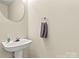 Clean half-bathroom featuring vanity sink, modern faucet, decorative wall mirror, and a towel holder at 10063 Reindeer Way Ln, Charlotte, NC 28216